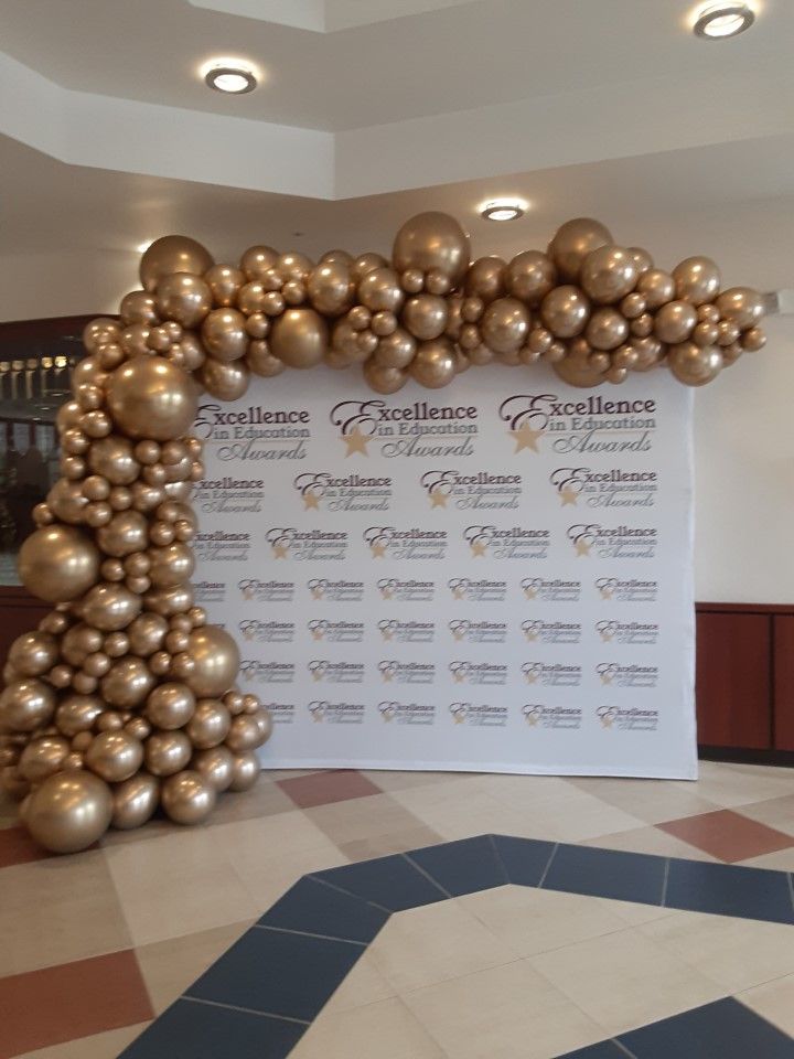 A wall with gold balloons and a sign that says excellence awards