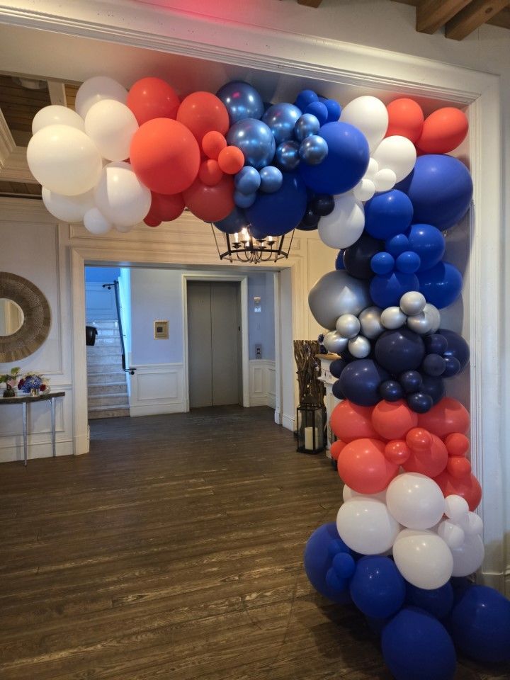 A room filled with red , white and blue balloons.
