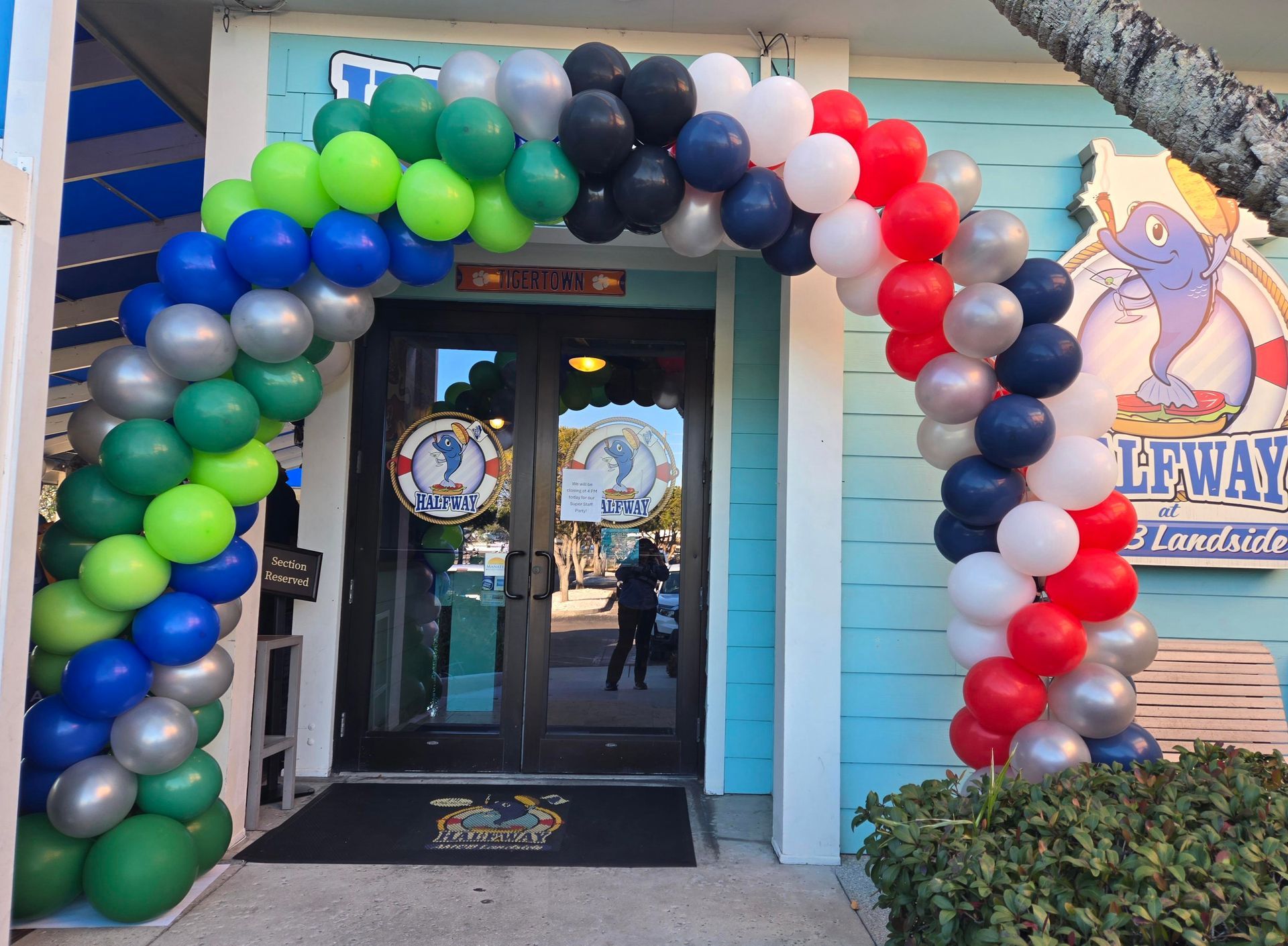 Entrance of a restaurant with a balloon arch in rainbow colors.