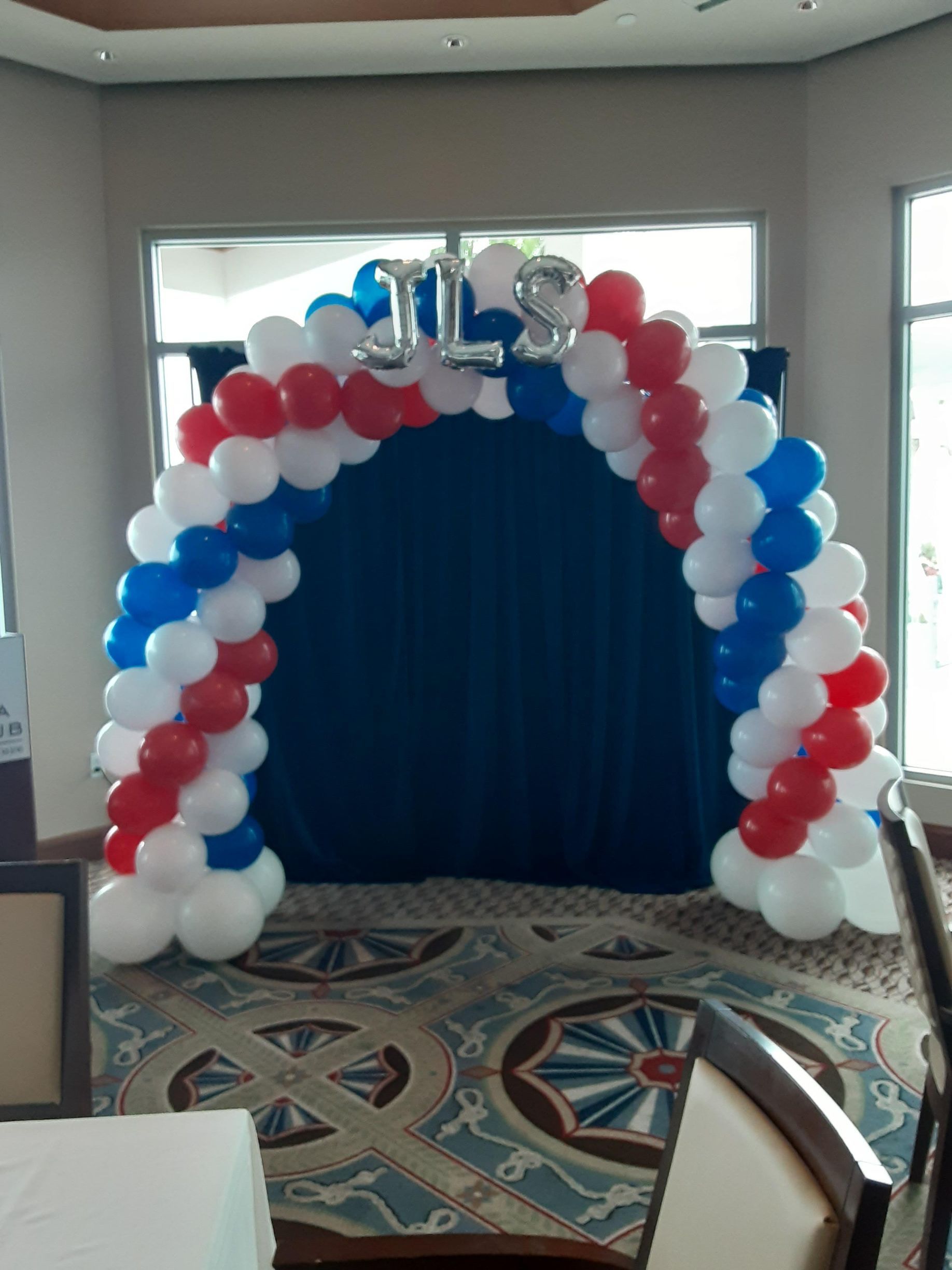 A festive balloon arch in red, white, and blue featuring silver 