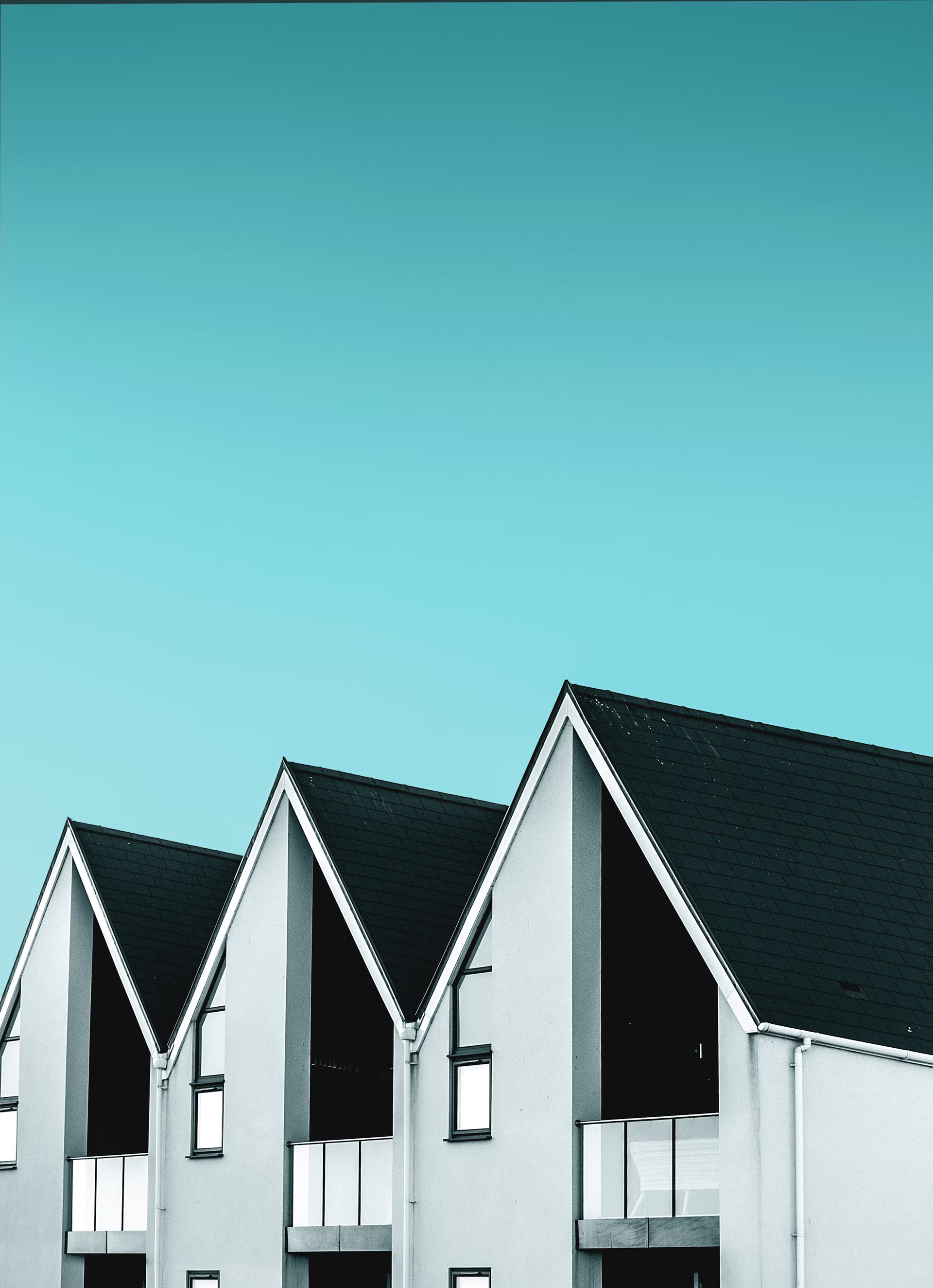 Three white houses are profiled against a blue sky.