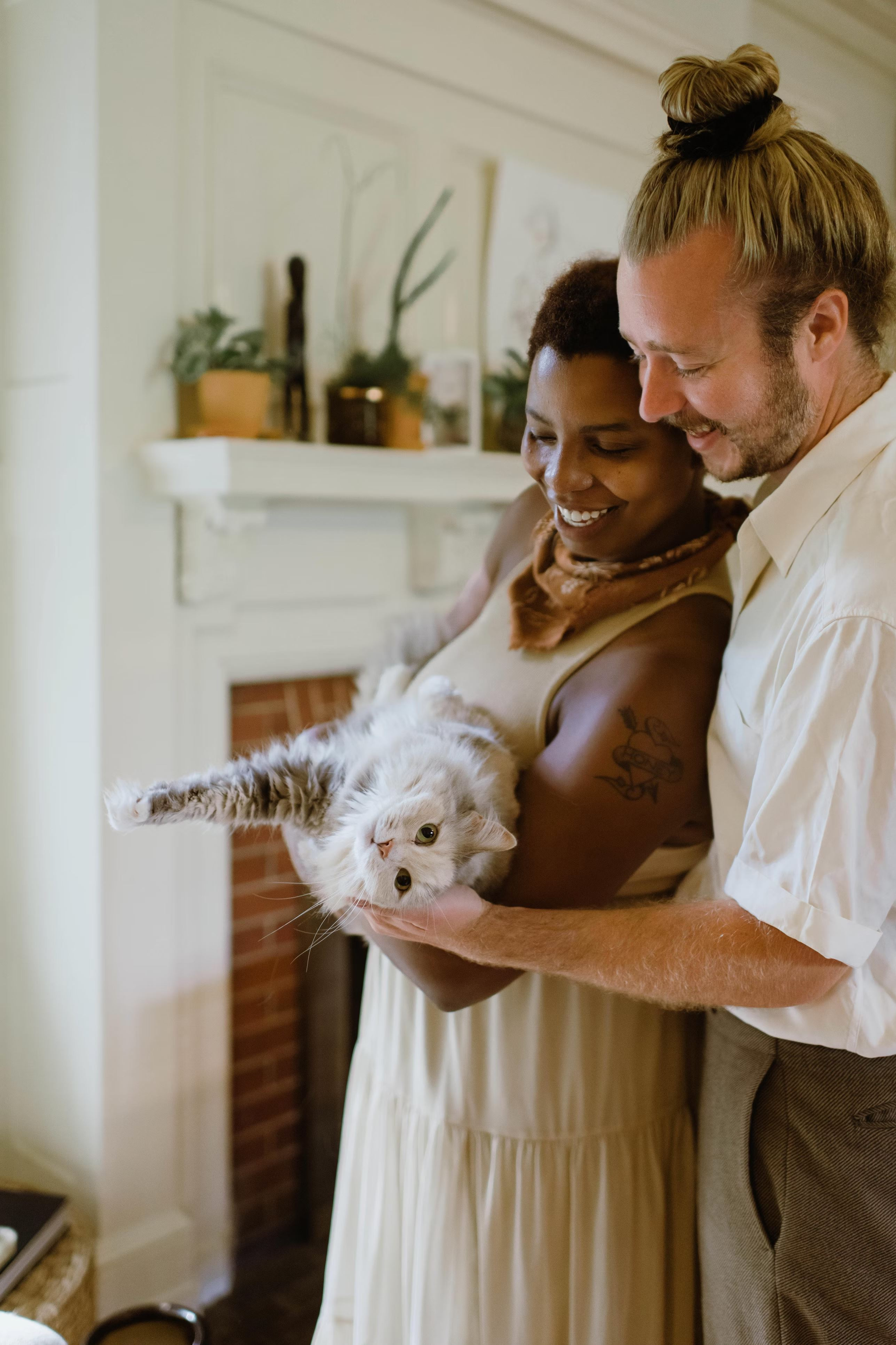 A heterosexual couple hugs their cat.