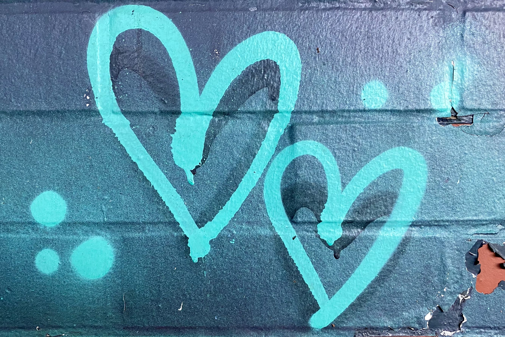 Two blue hearts are spray-painted on a wall.