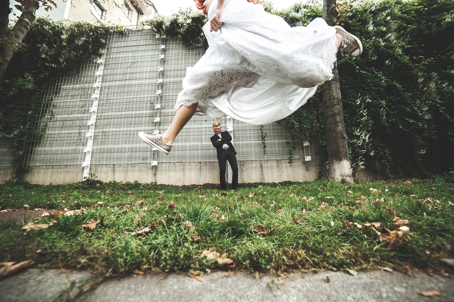 A bride jumps joyfully near her groom. 