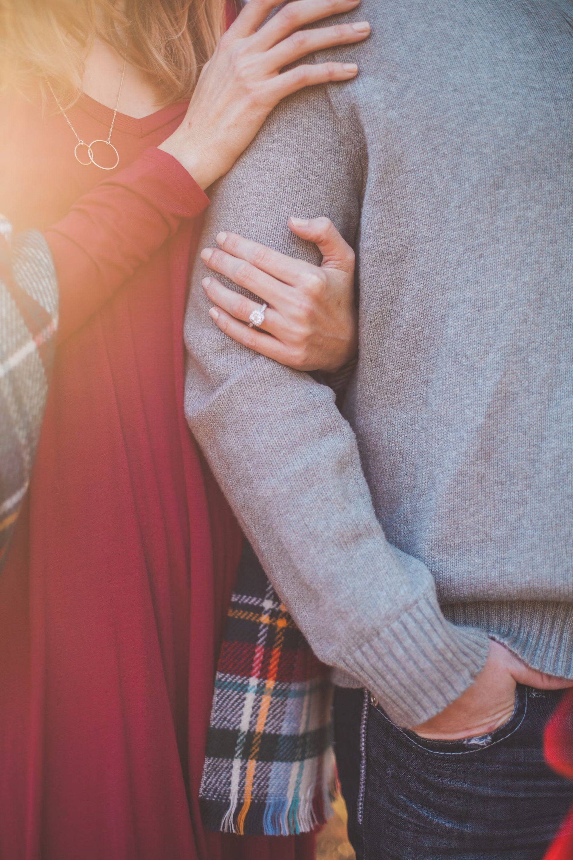 A man and  a woman cuddle as her diamond engagement ring sparkles.