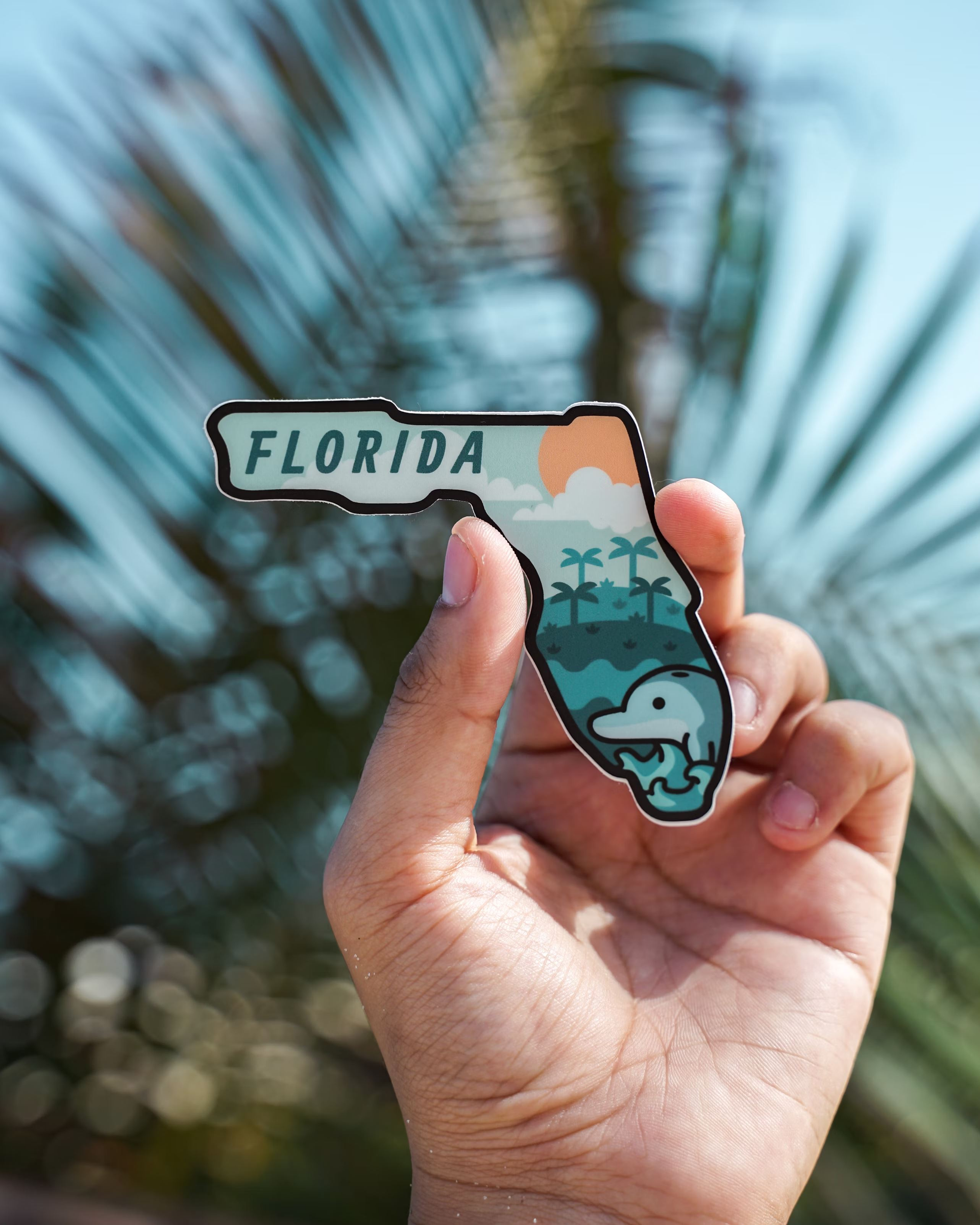 A hand holds a small ornament in the shape of the state of Florida.