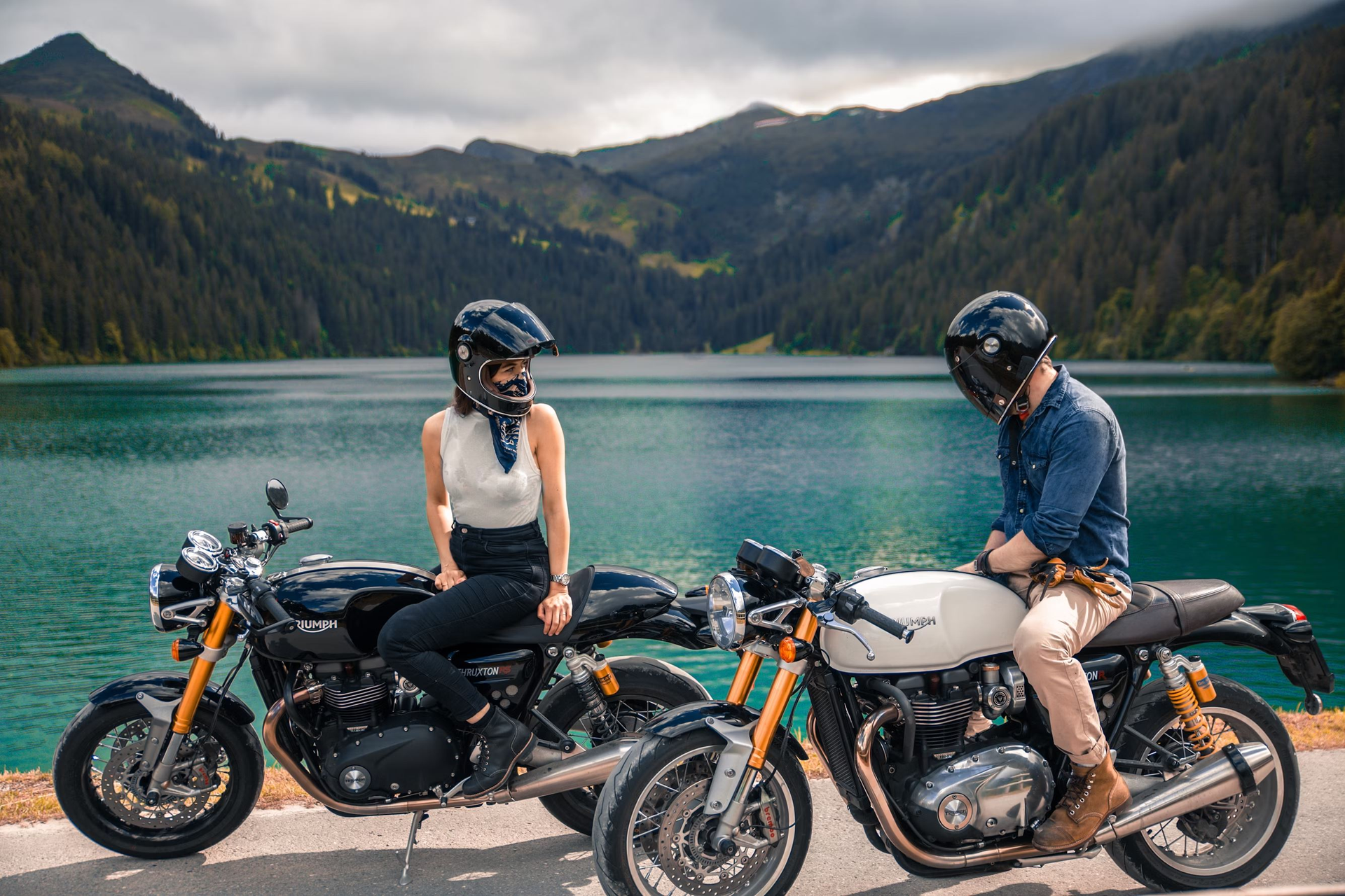 A heterosexual couple stops on their motorcycles by the lake. 