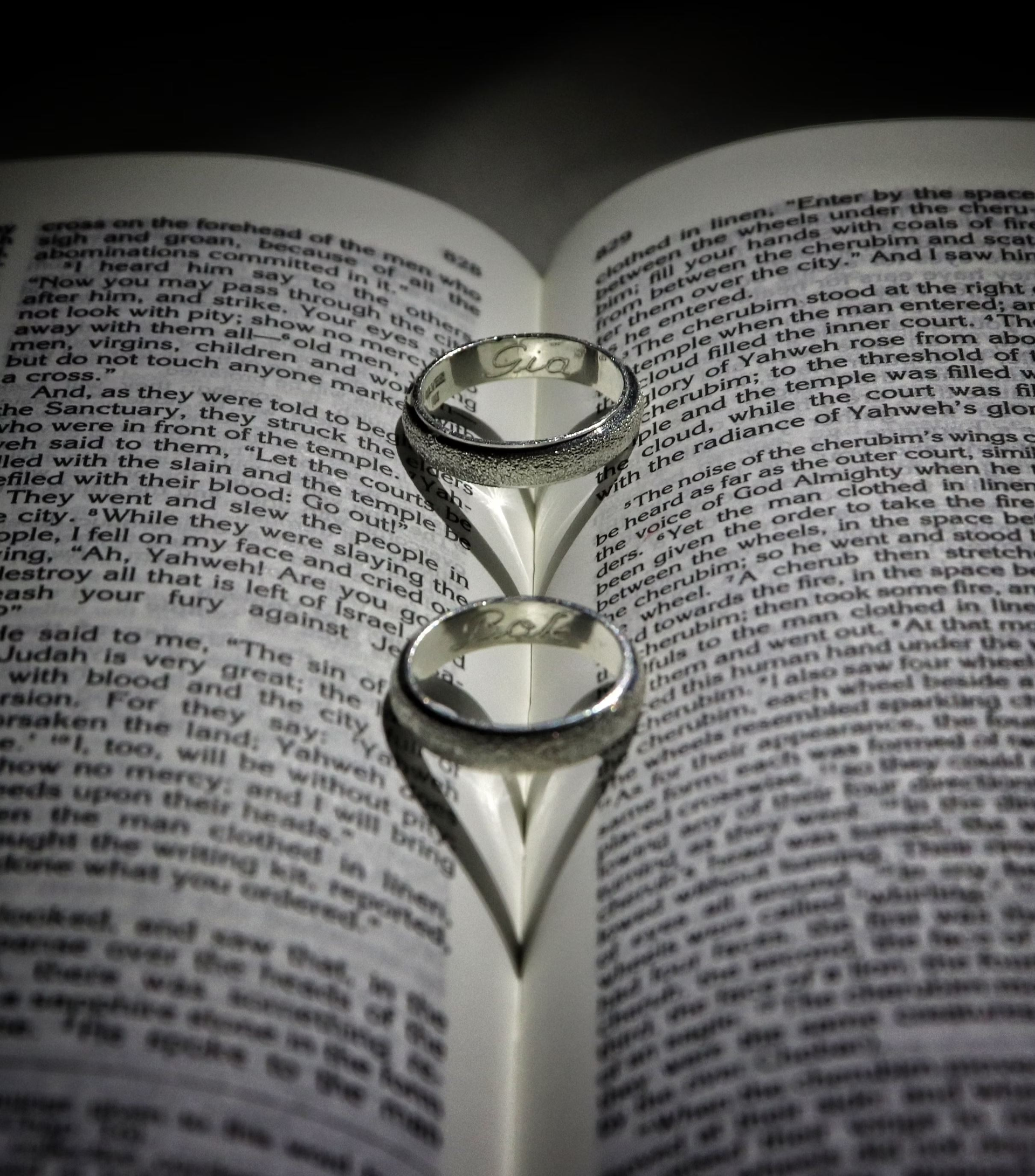 Two wedding bands sit in an open Bible.