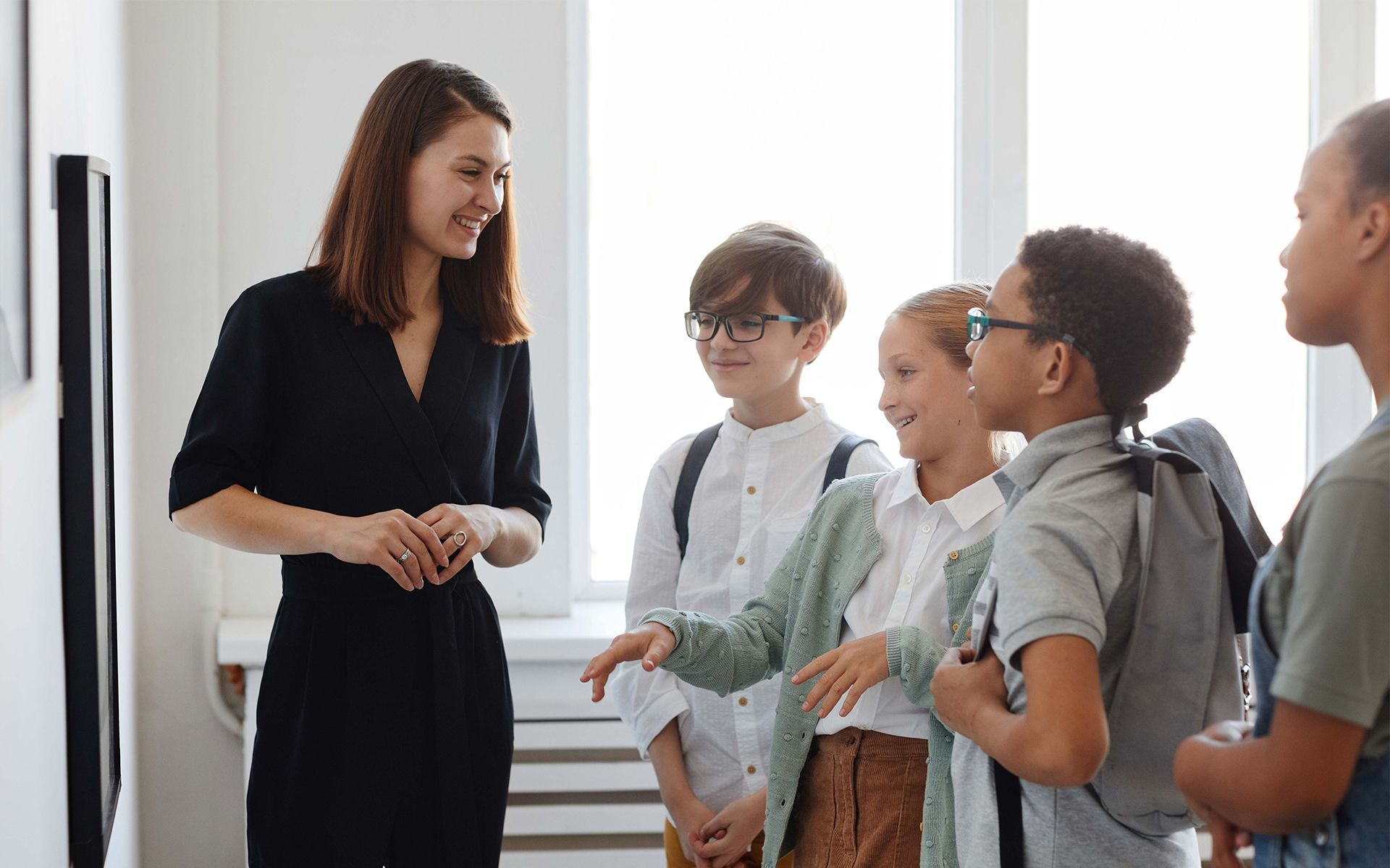 Teacher speaking to a small group of students in a bright classroom