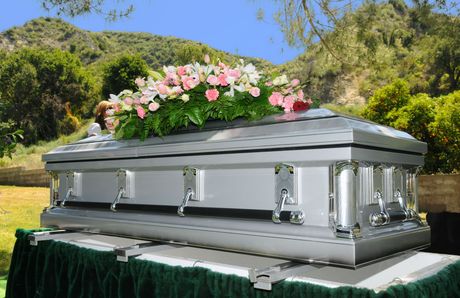 A silver coffin with pink flowers on top of it