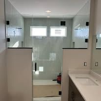 A bathroom featuring a glass-enclosed shower with a floating mirror above it and a vanity with a white countertop.