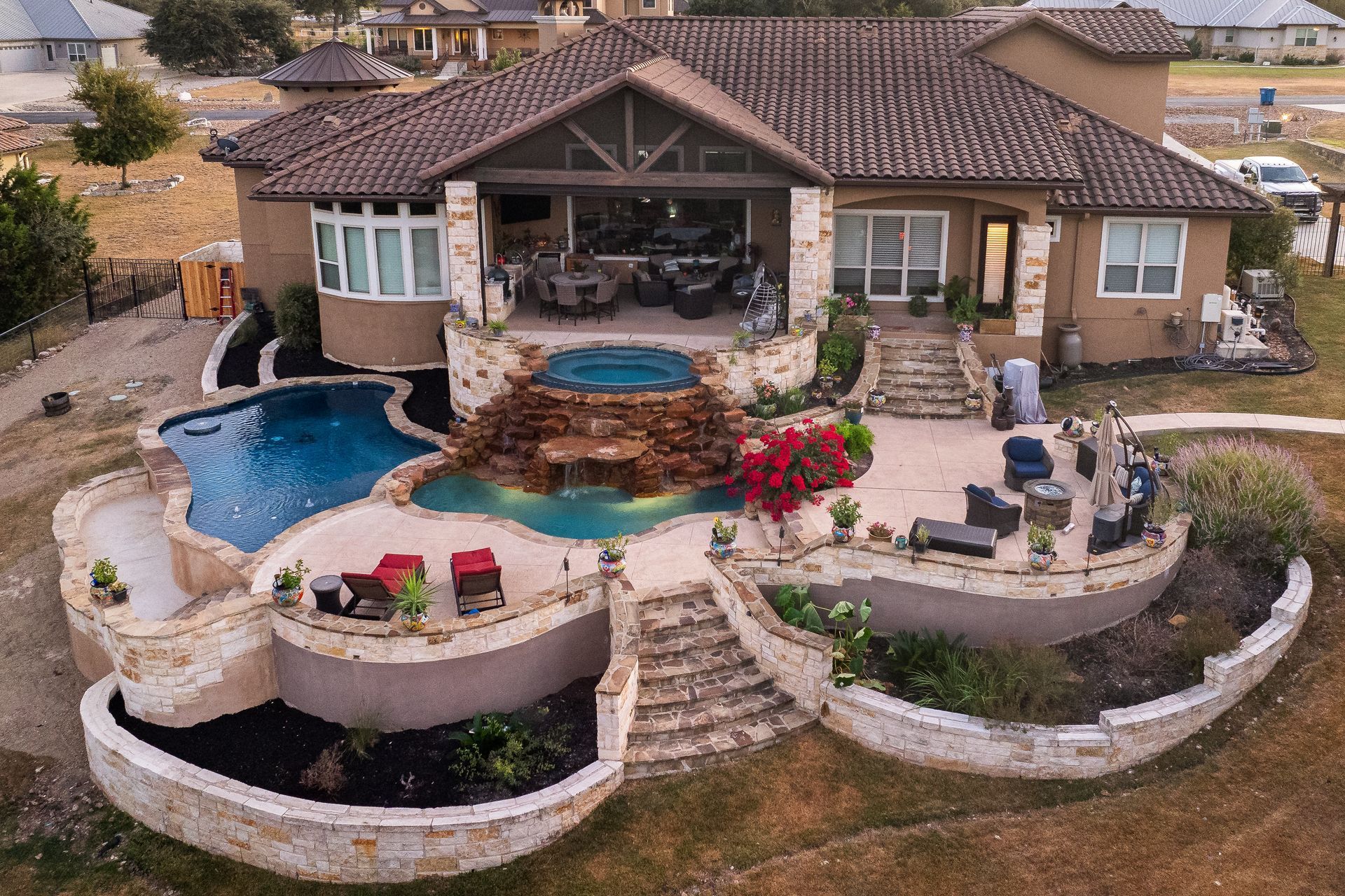 Luxury home with pool, spa, and patio, overlooking a grassy area.