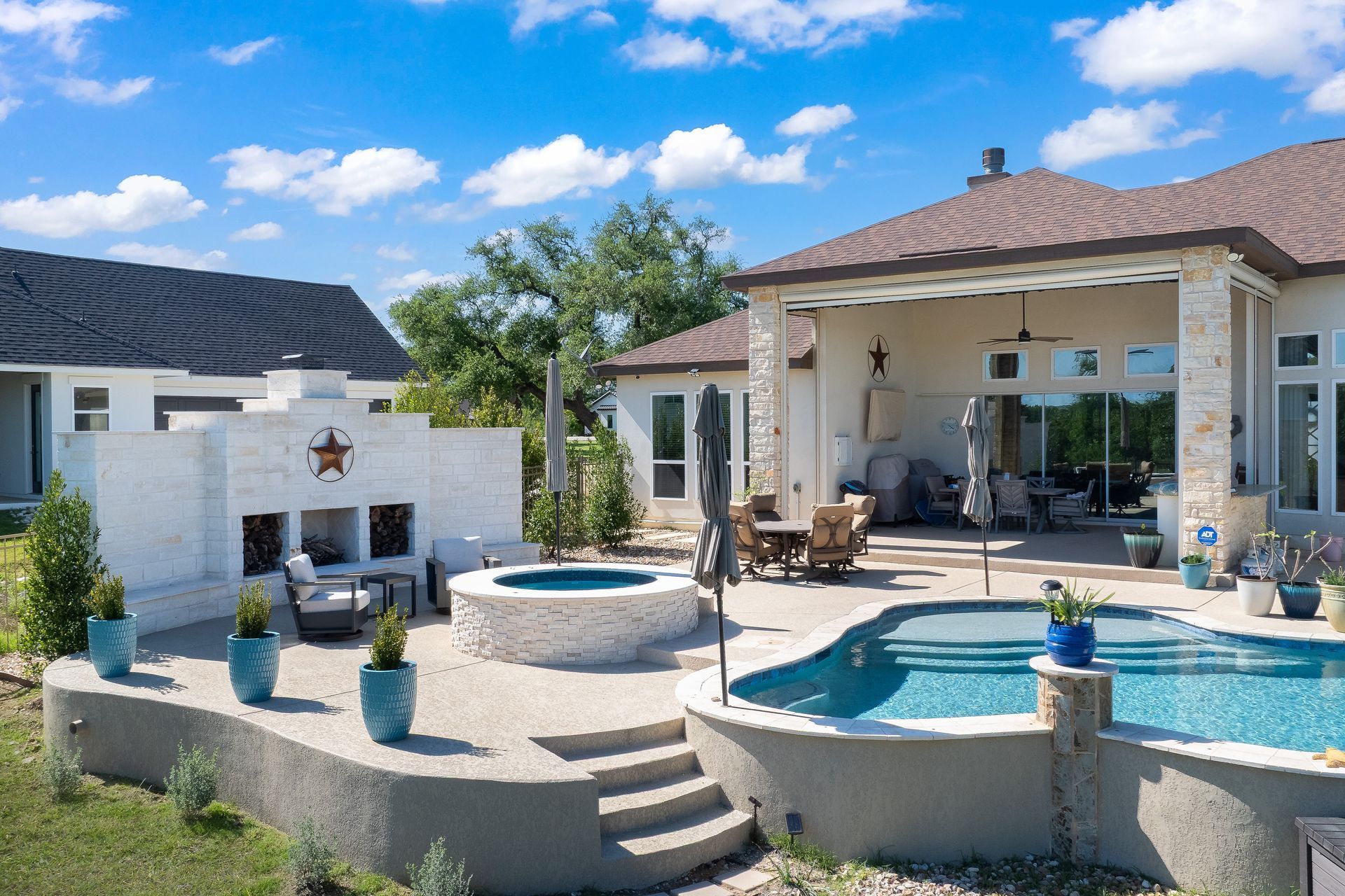 Backyard patio with pool, hot tub, fireplace, and outdoor seating.