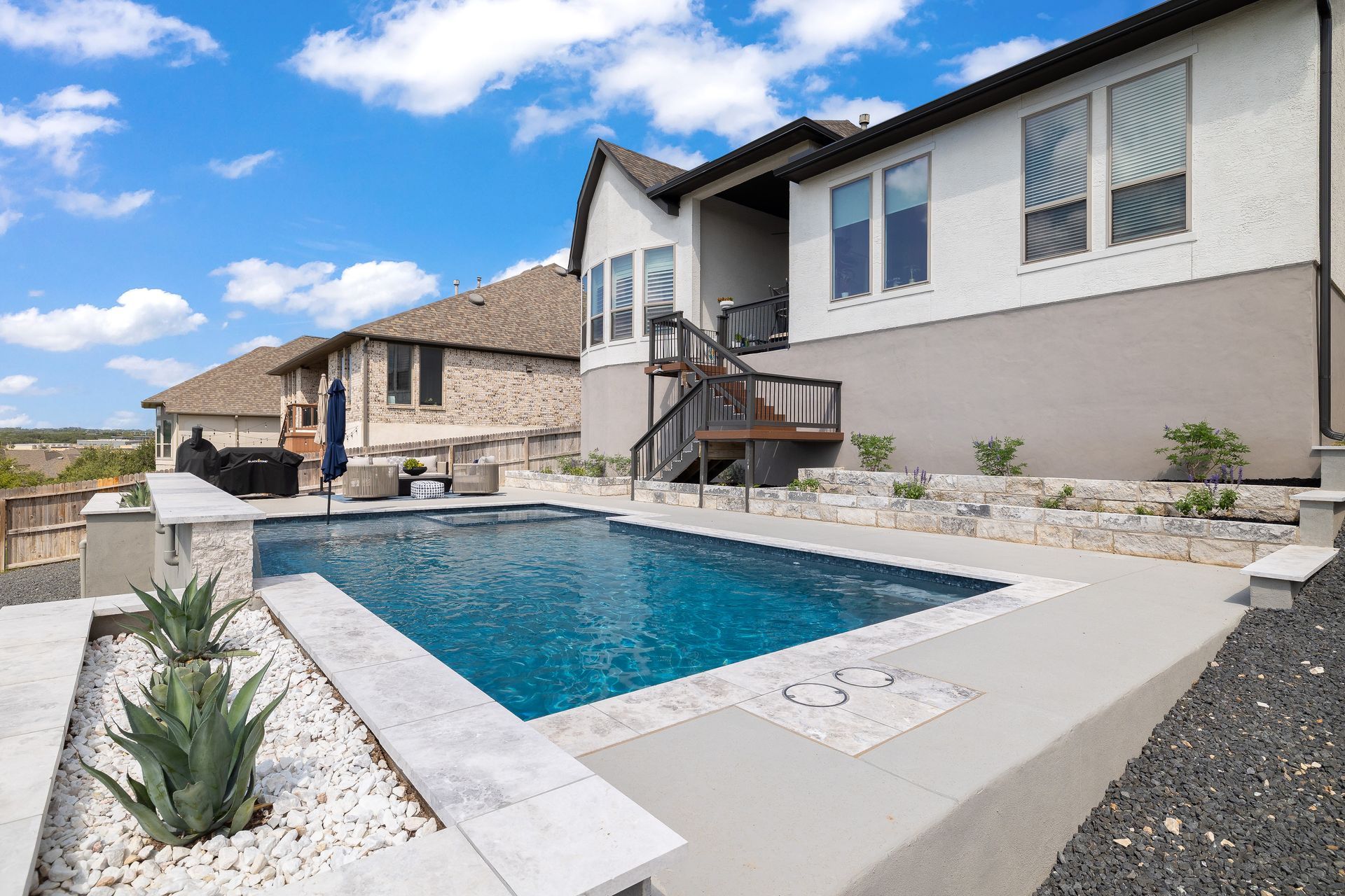 Backyard pool next to a house on a sunny day.