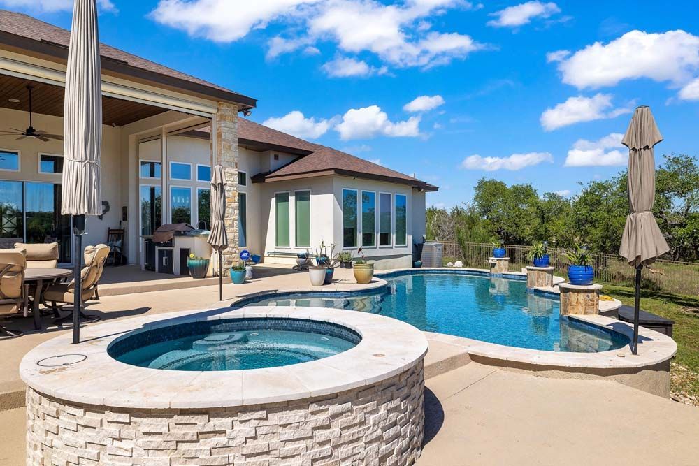 Luxury home with a pool and hot tub on a sunny day.