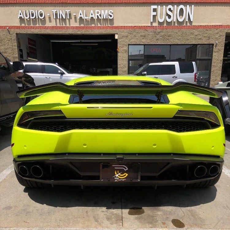Neon green Lamborghini rear view parked outside an audio shop with black accents and dual exhausts