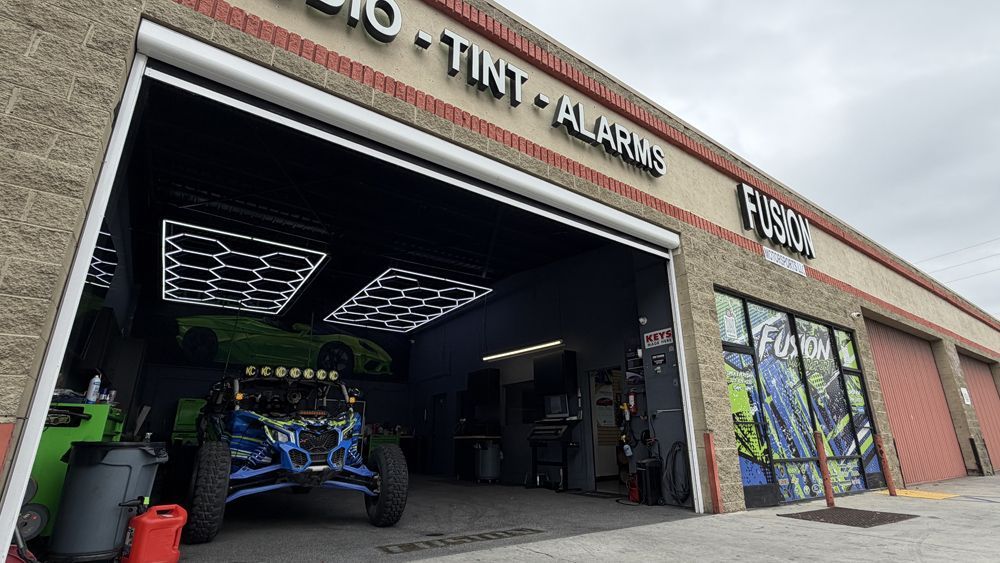 Open auto shop garage with off-road vehicle, bright ceiling lights, and colorful wall art