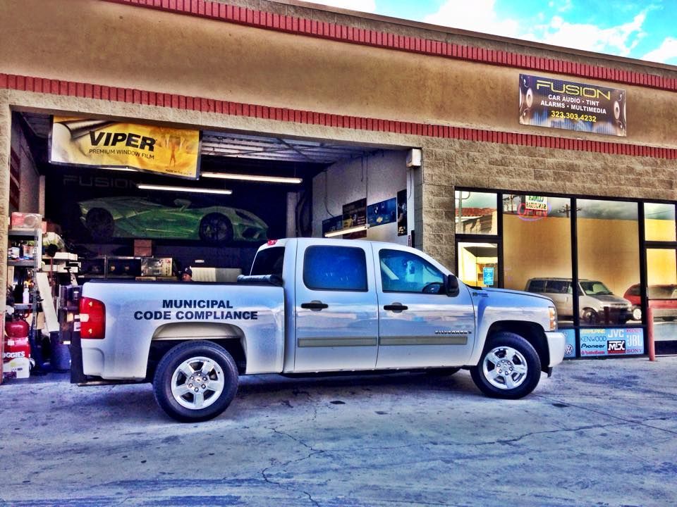 A silver Municipal Code Compliance pickup truck parked in front of a automotive business with a Viper banner.