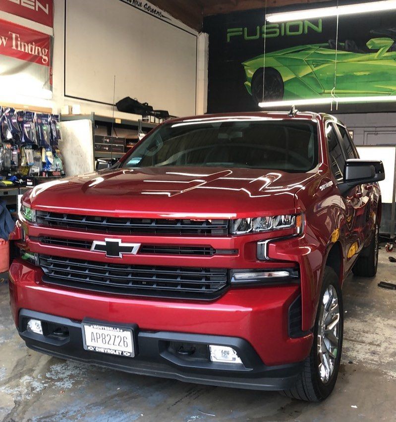 A shiny red Chevrolet pickup truck parked inside a bright workshop with a 