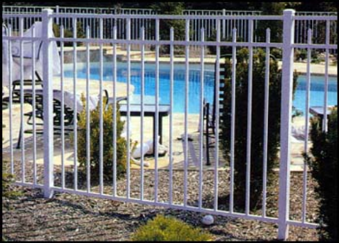 White metal fence surrounding a pool, with a patio area, and landscaping.