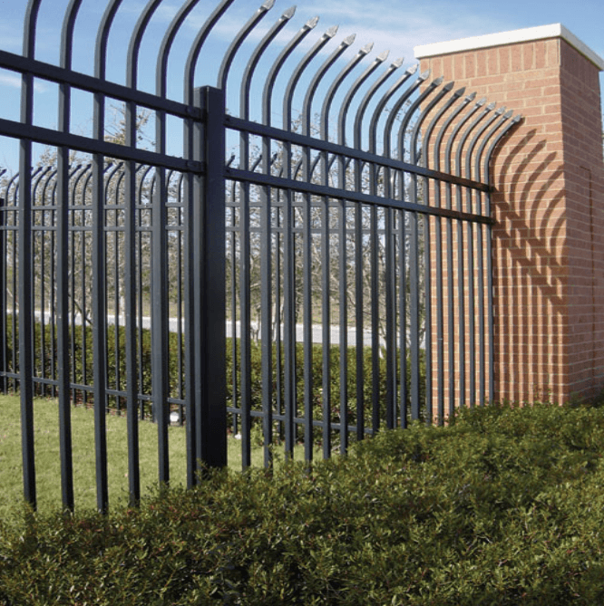 Black metal fence with arched top, brick pillar, and green bushes.