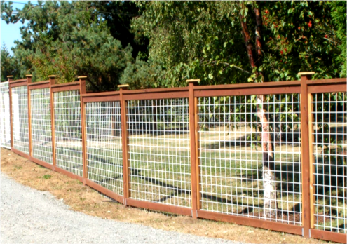Brown framed fence with white wire mesh, gravel pathway, and trees in background.