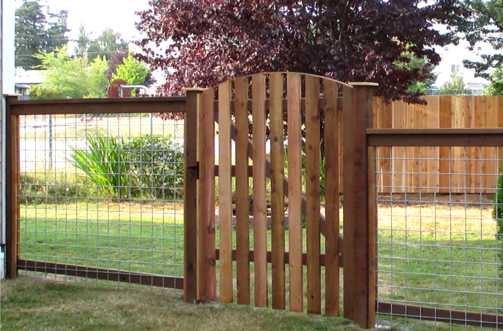 Wooden gate and fence with wire mesh panels in a grassy yard.
