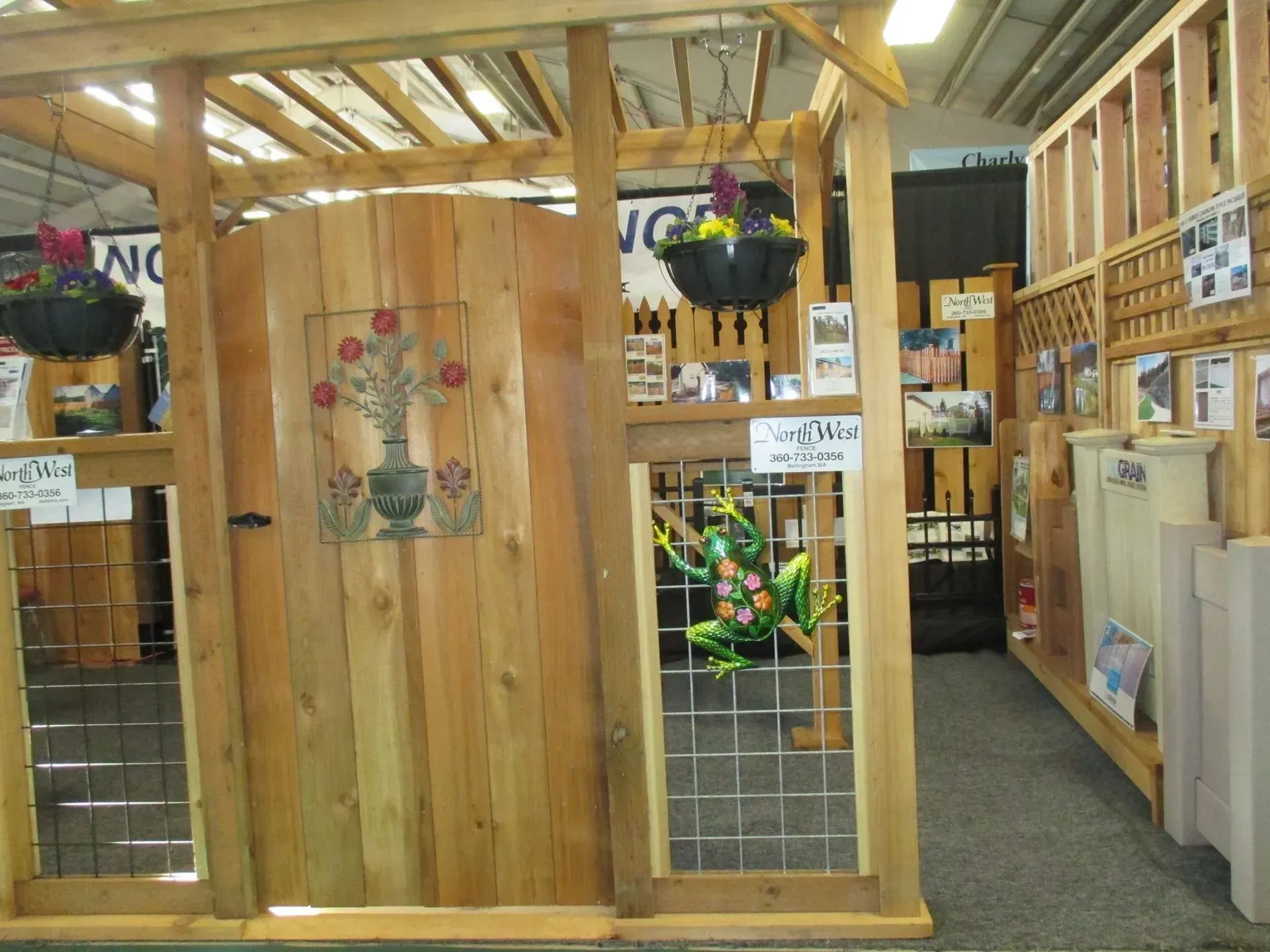 Wooden arbor with hanging baskets and a decorative door, inside a store.