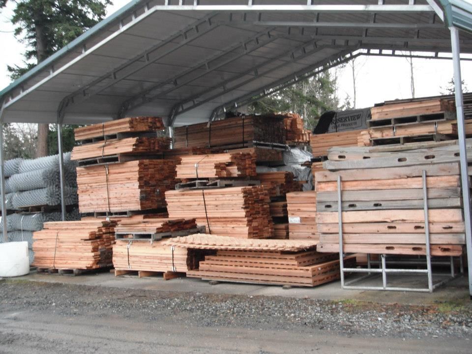 Lumber stacked on pallets under a metal canopy.