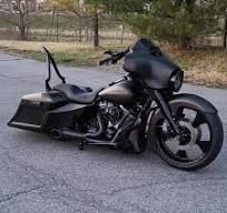 Black custom motorcycle parked on a road, with a low fairing and tall sissy bar.