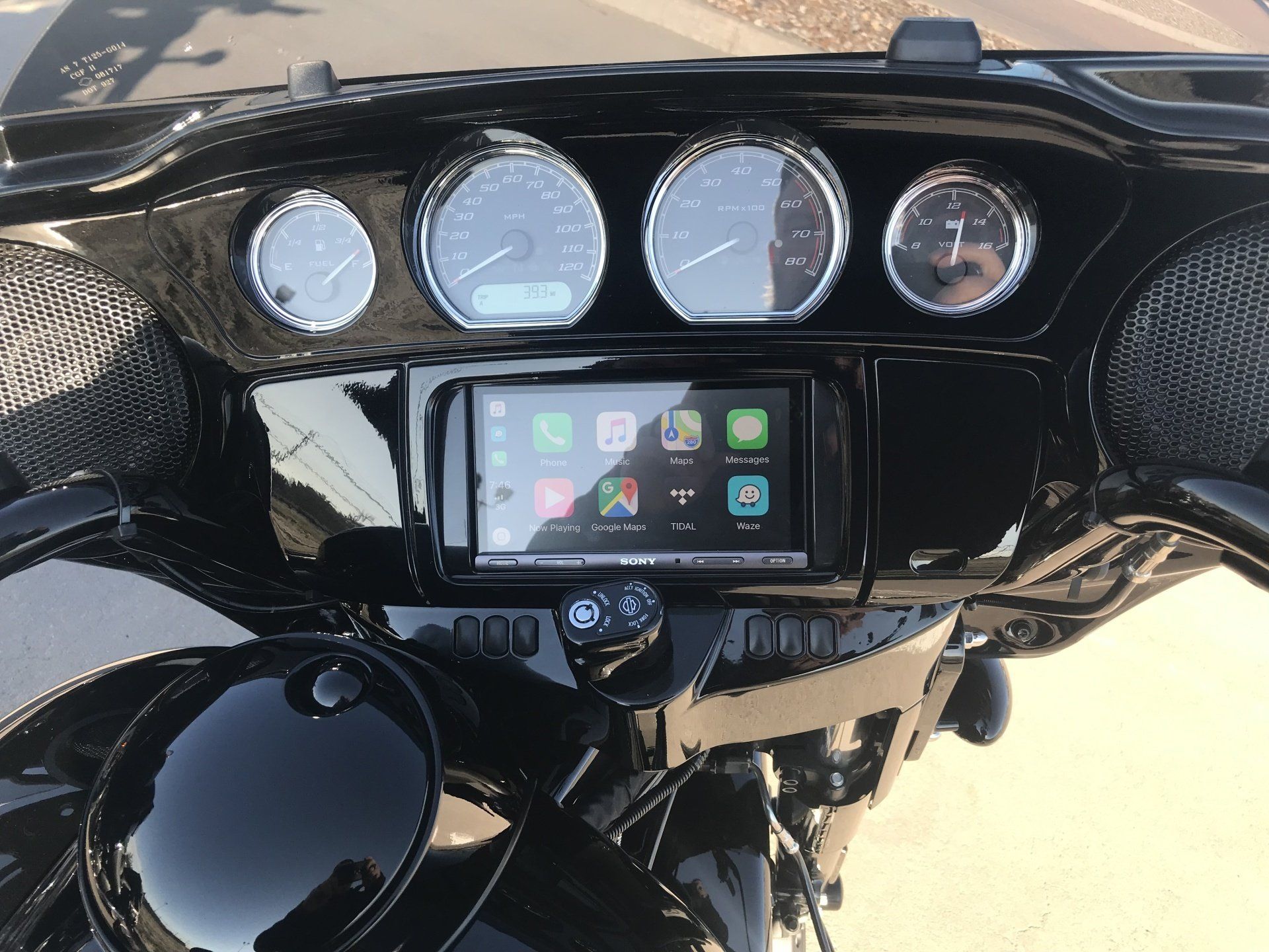 Motorcycle dashboard with four gauges and a central touchscreen infotainment display, glossy black fairing