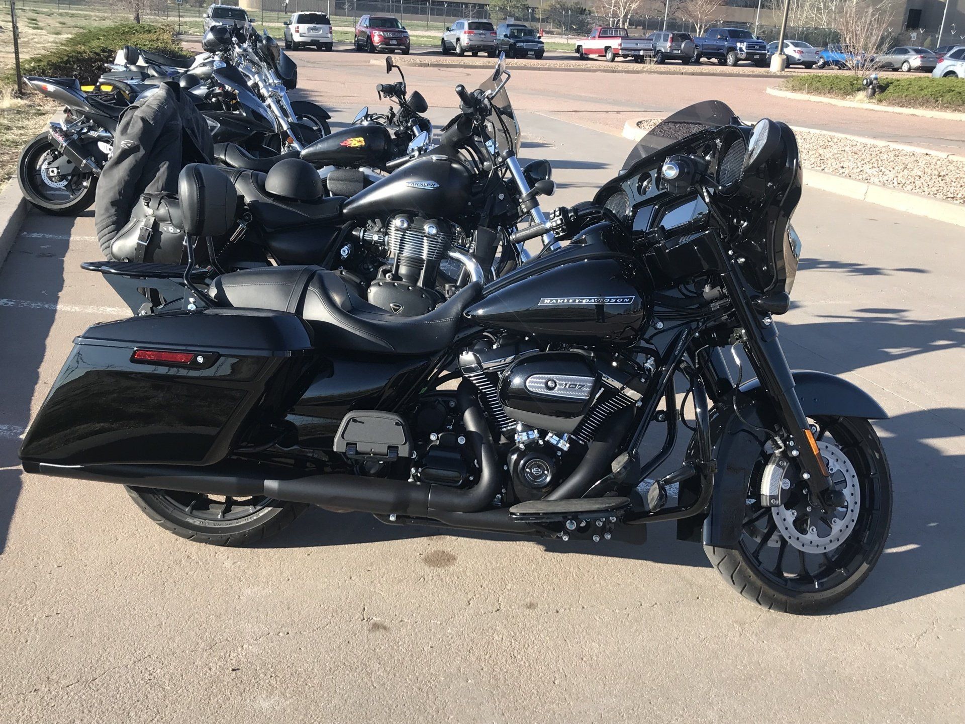 Black touring motorcycles parked in a row on a sunny paved lot