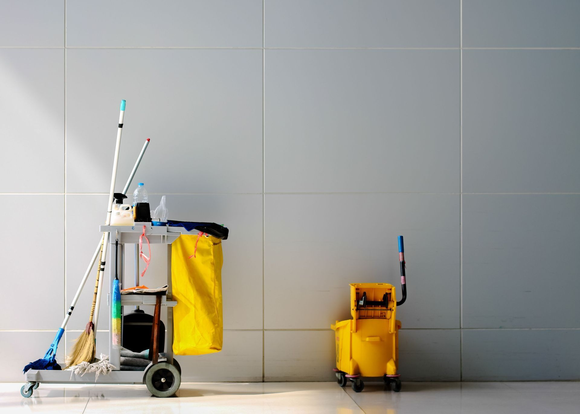 a cleaning cart is sitting next to a yellow bucket
