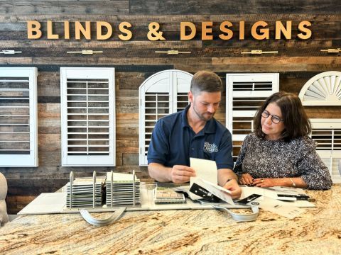 Blinds and designs showroom with two people reviewing samples at a wooden table
