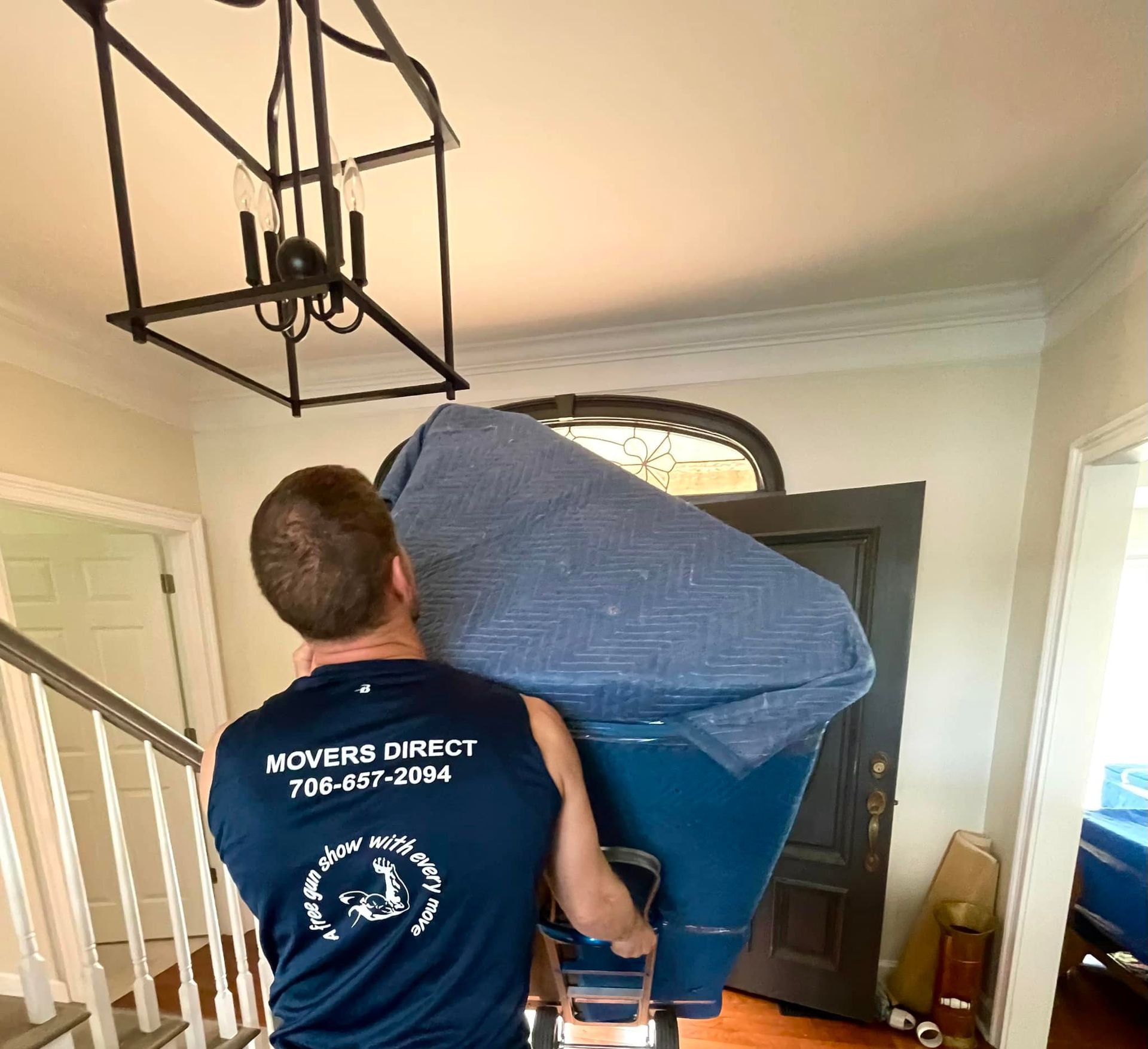 A man is carrying a couch on his shoulders in a room.