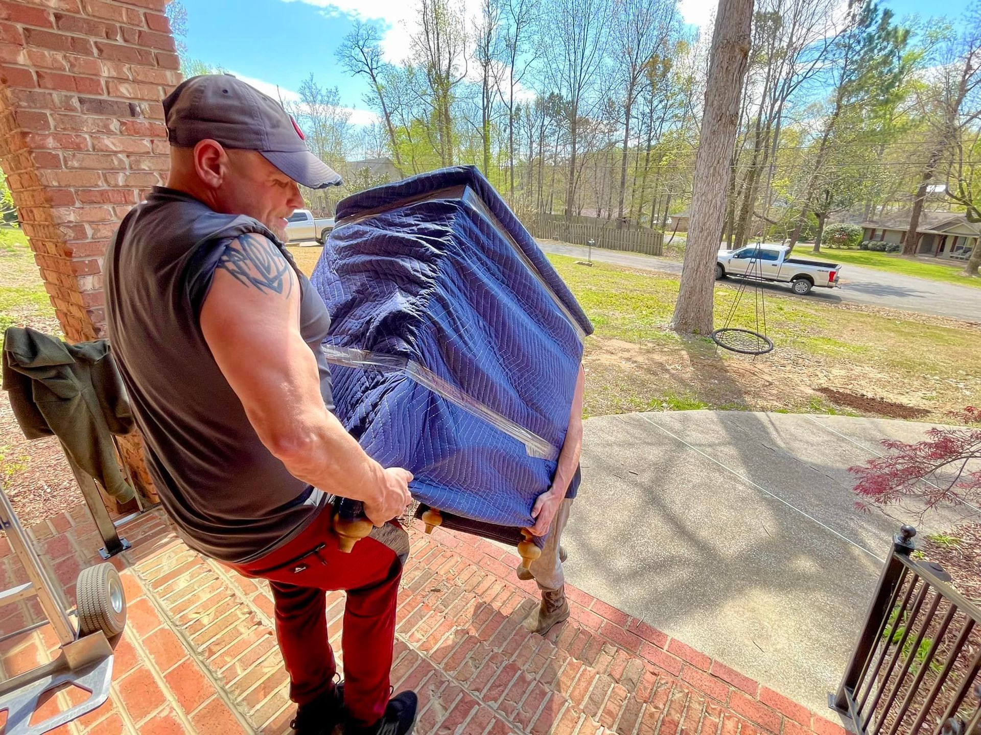 A man is carrying a chair on a dolly on a porch.