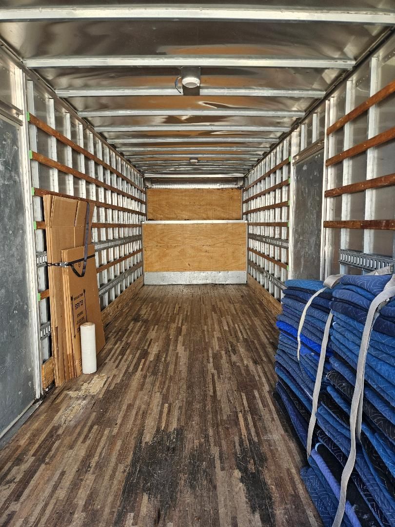 The inside of a moving truck filled with boxes and blue blankets.