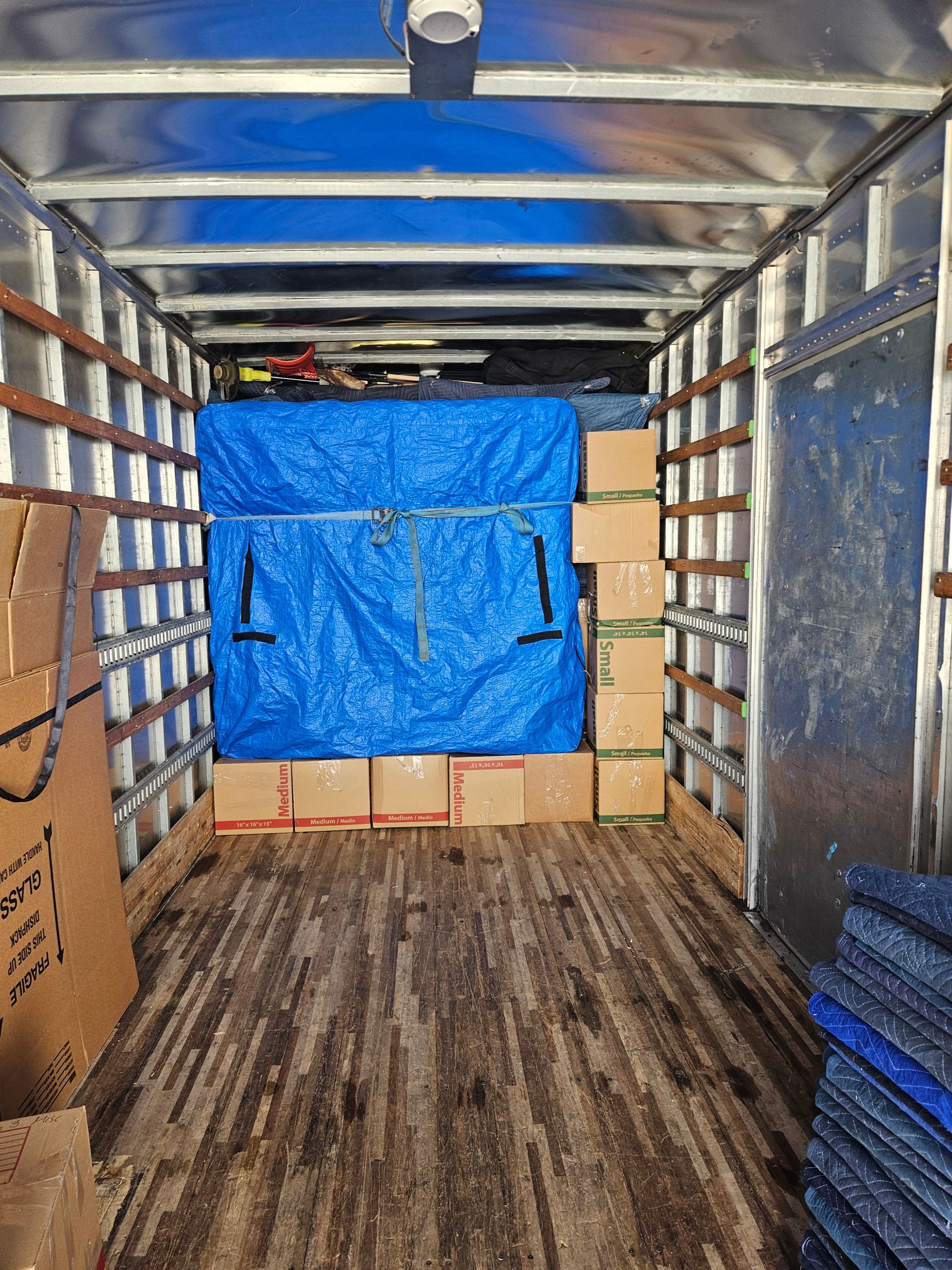 Long view of boxes in a moving van covered with a blue tarp.