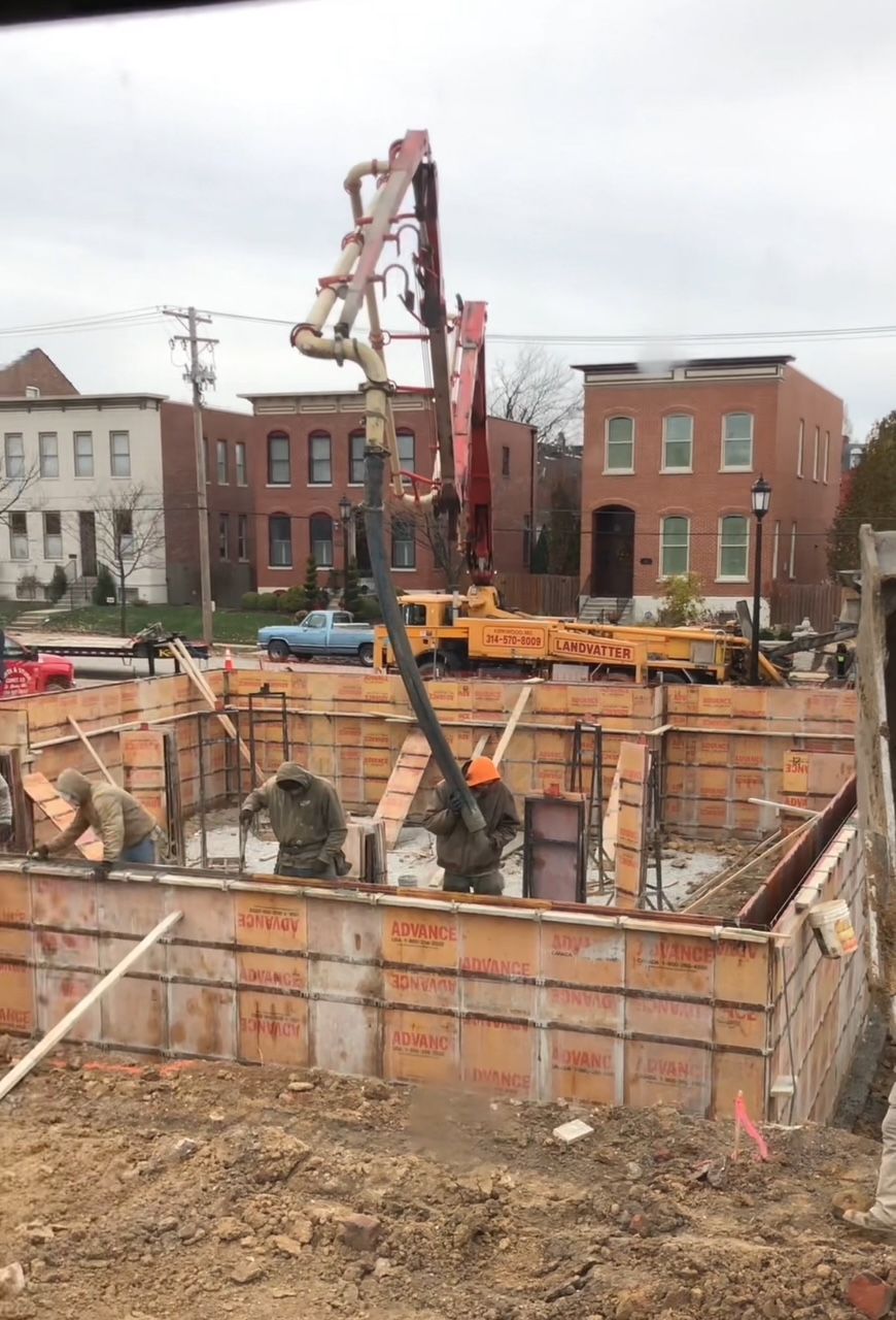 A construction site with a crane pumping concrete into the ground.