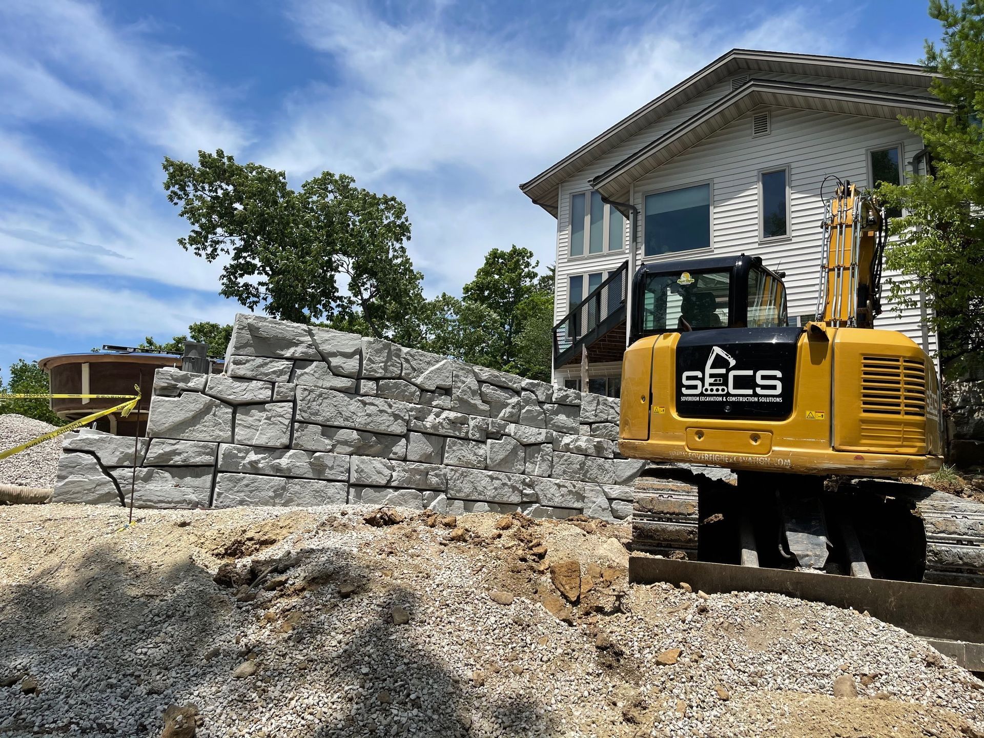 A yellow excavator is parked in front of a house.