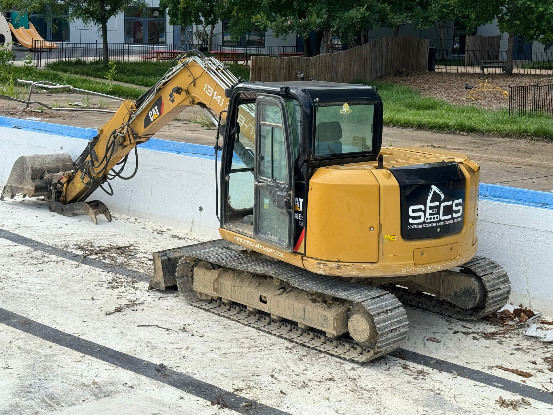 A small excavator is sitting on top of a concrete surface.