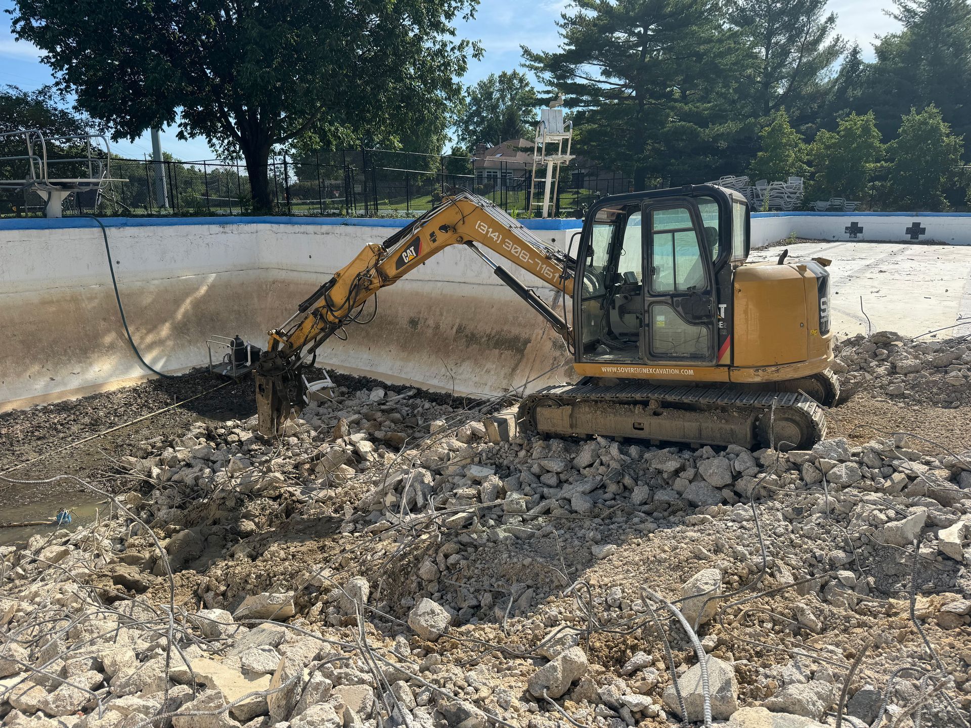A yellow excavator is digging a hole in a pile of rocks.