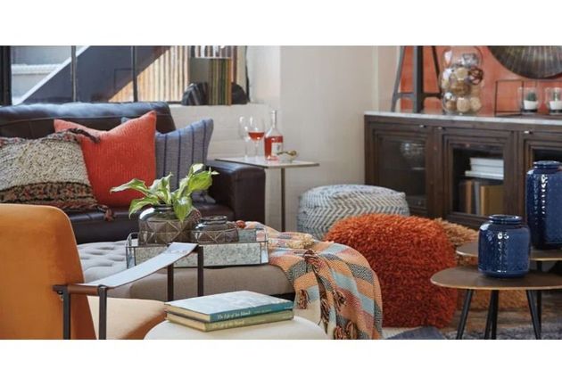 Stylish living room with sofa, coffee table, side chairs, and colorful throw blankets.