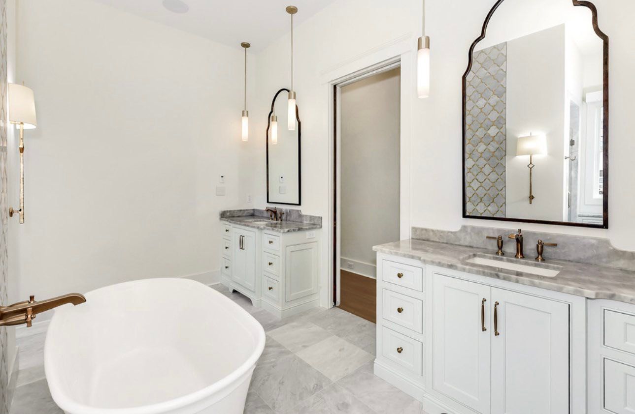 Bright white bathroom with freestanding tub, double vanity, mirrors, and pendant lights