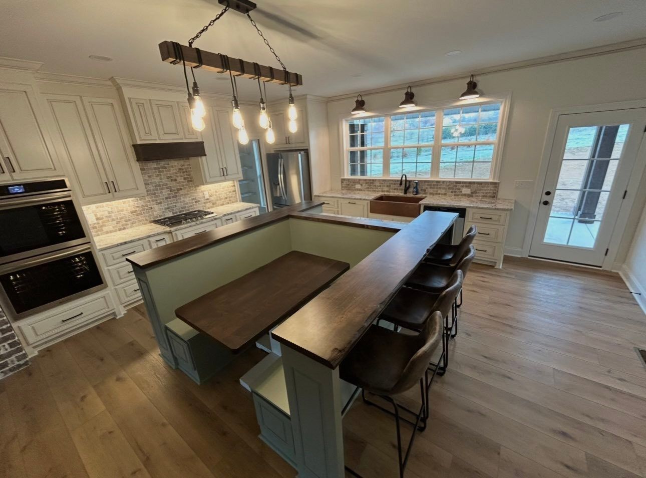 Modern kitchen with large island, pendant lights, white cabinets, and wood floors