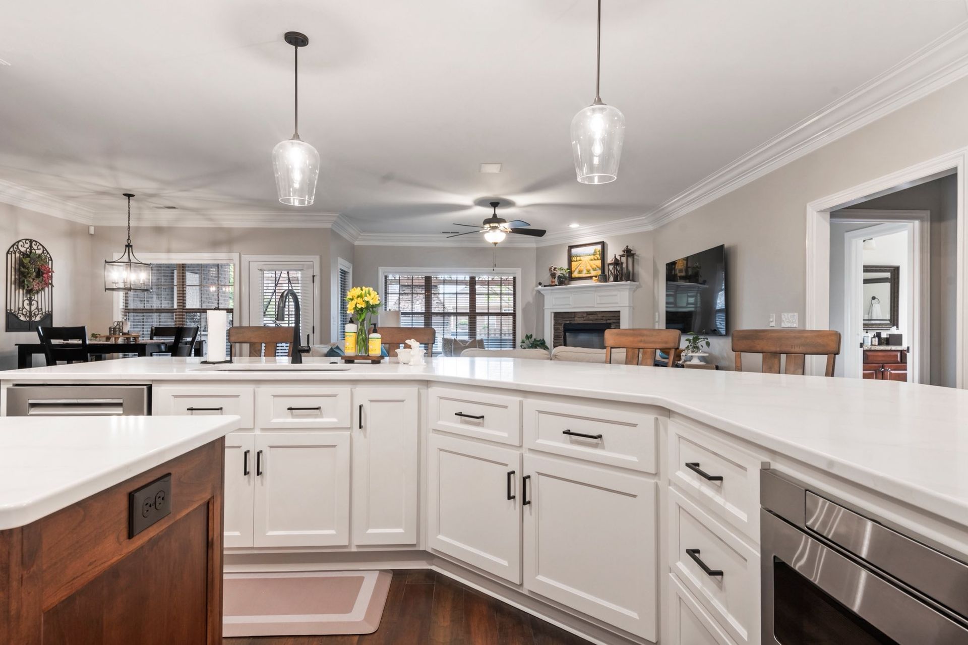 Bright modern kitchen with white cabinets, island counter, pendant lights, and open view into dining area