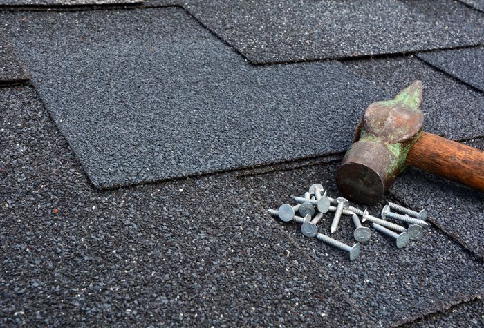A hammer and nails are laying on top of a roof.