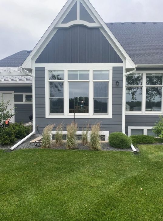 A house with a lot of windows and a large lawn in front of it.