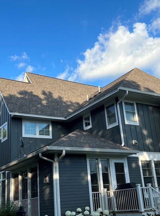 A large house with a gray siding and a brown roof.