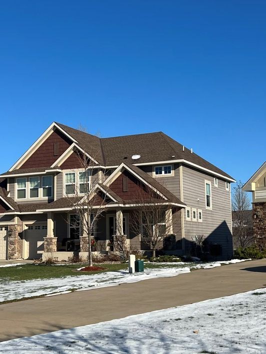 A large house with a snowy driveway in front of it.
